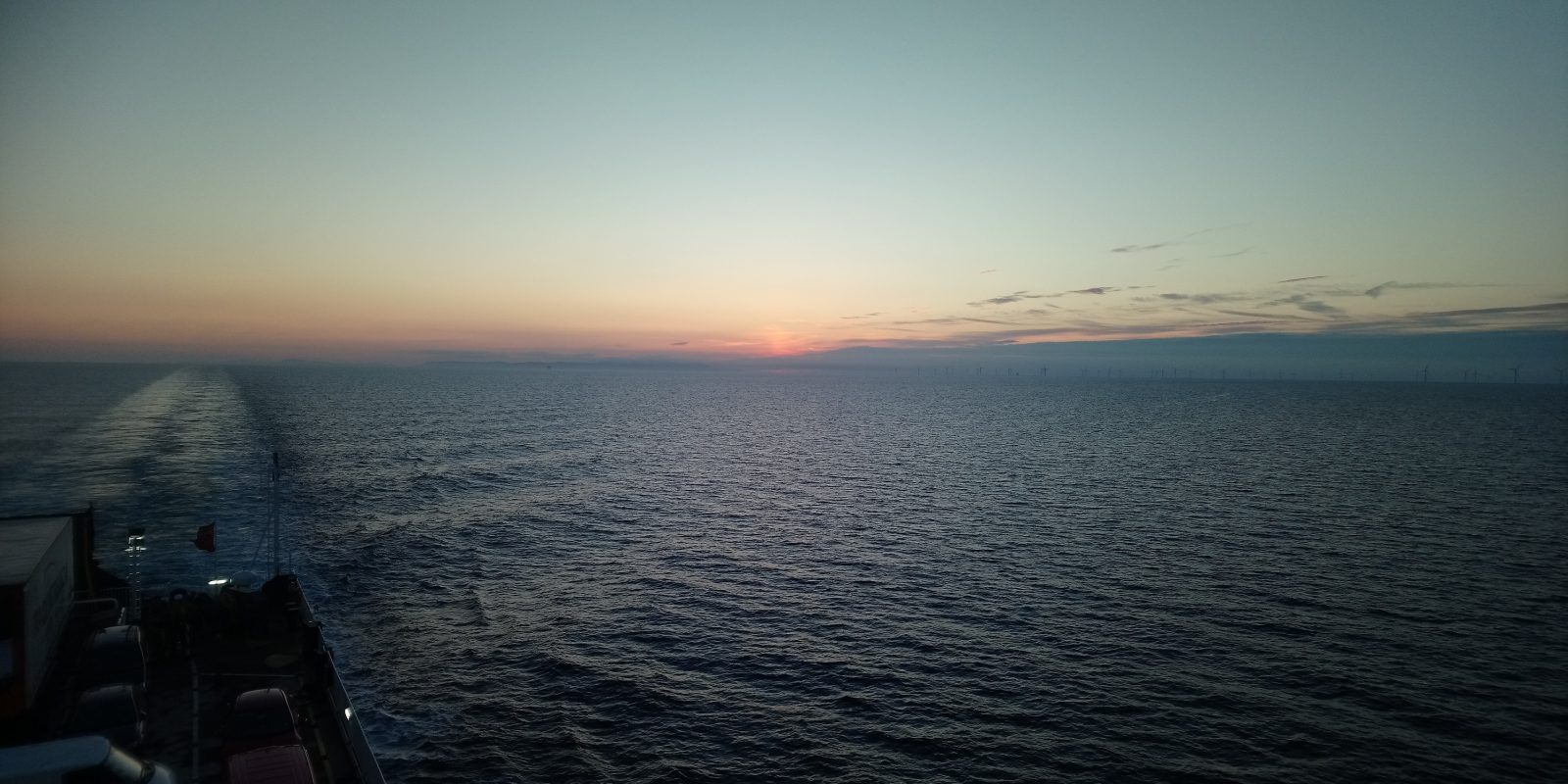 iew from the back of Steam Packet Company vessel Ben-my-Chree with miles of sea on display in addition to a orange sunset and blue sky