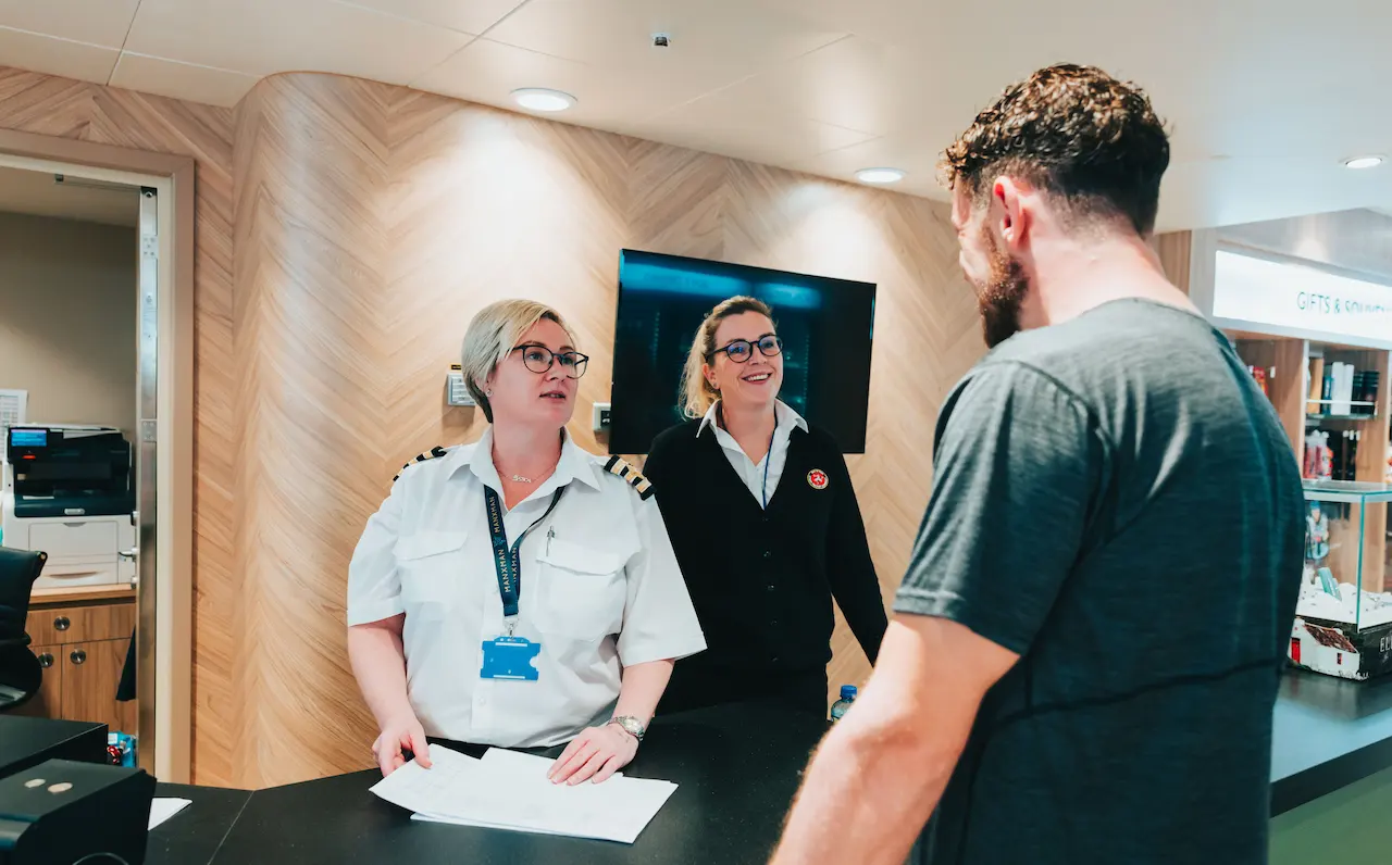 Passenger Services Officers on Manxman assist a customer with an enquiry at the ship's information desk