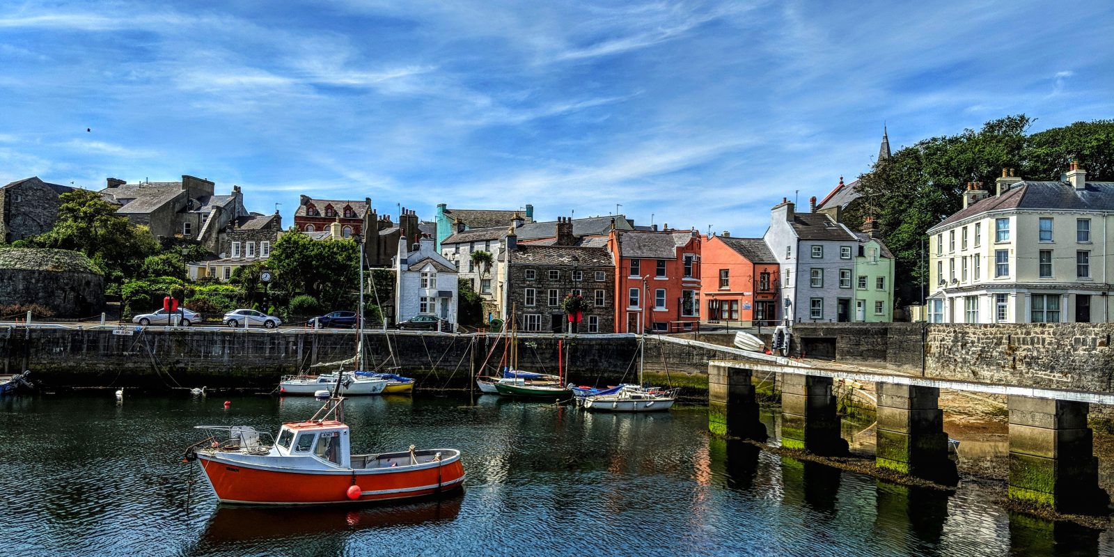 Boats sitting in Castletown Harbour on a sunny day with colourful houses in the background