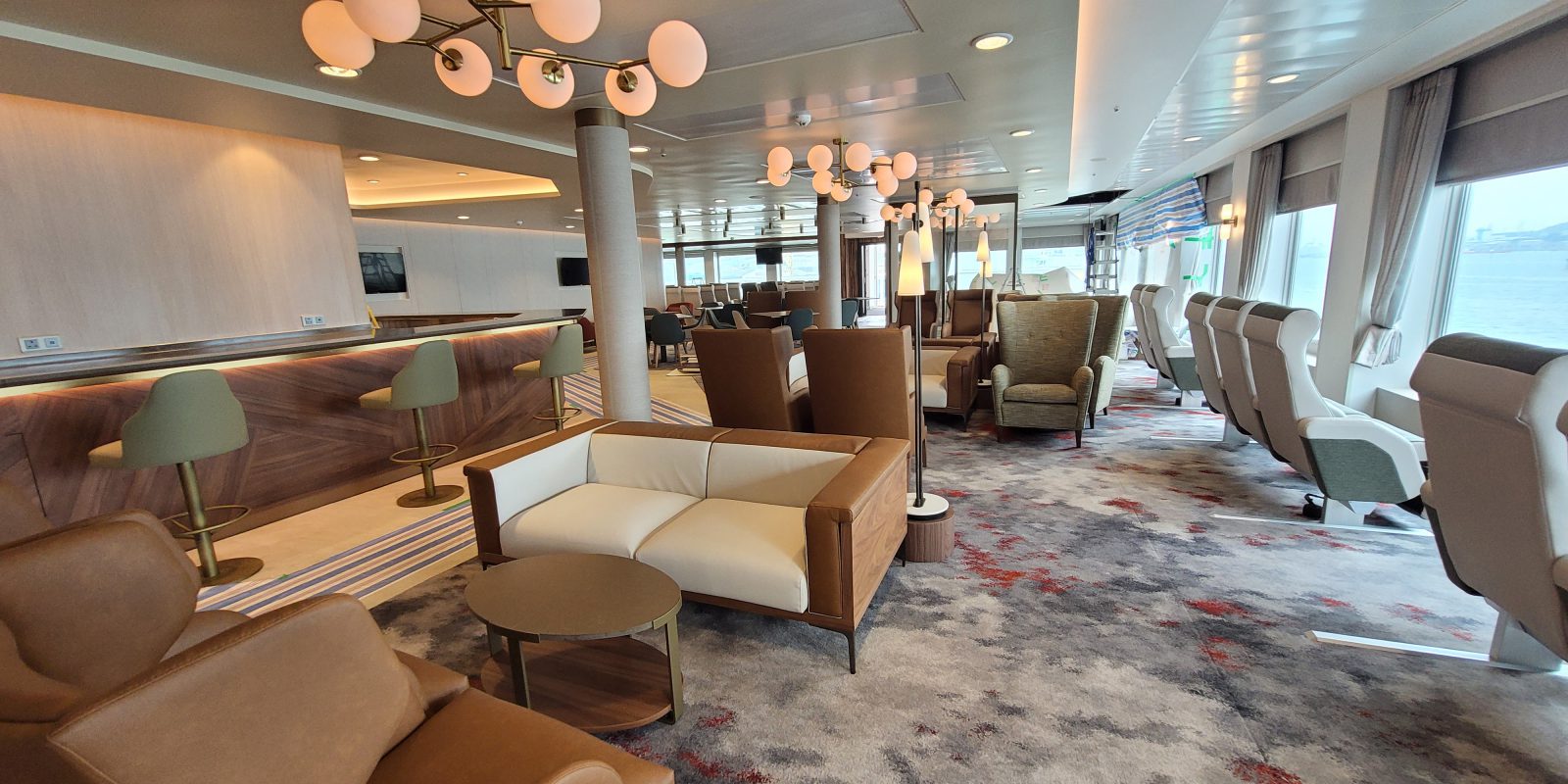 Lounge are with bar with stools, sofas and armchairs facing out to see on a ferry