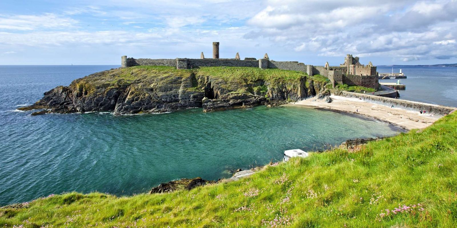 View of castle on Isle of man from the grassy coastline on a sunny day